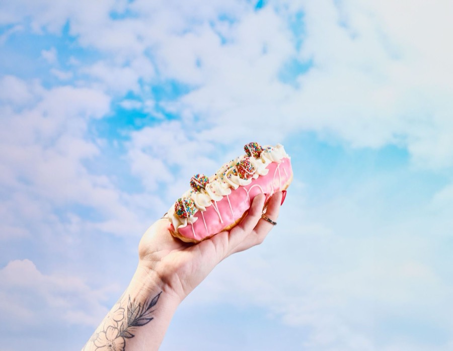 Pink dessert held up against a blue sky