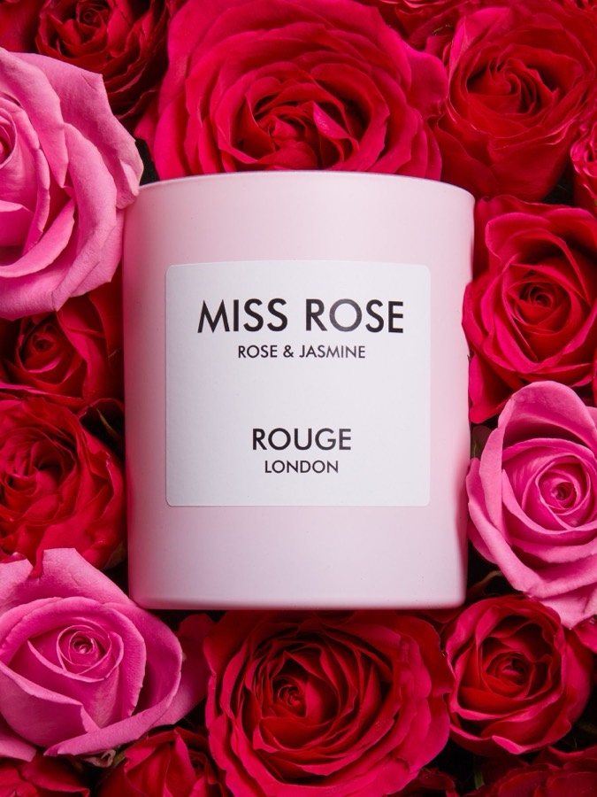 Miss Rose fragrance by Rouge London displayed among red and pink rose petals.